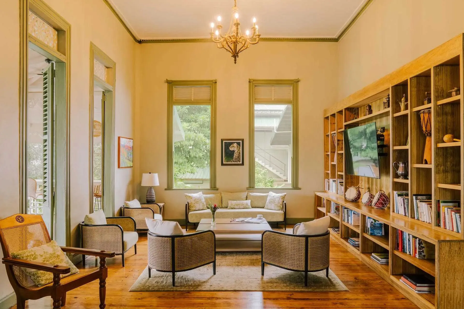 Light-filled sitting room with cane chairs and a wooden bookshelf